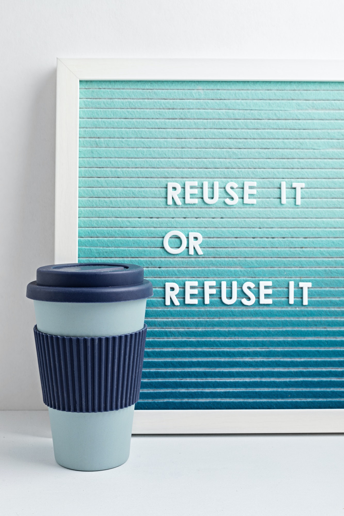 Reusable coffee cup and letterboard with text reuse it or refuse it. Zero waste sustainable