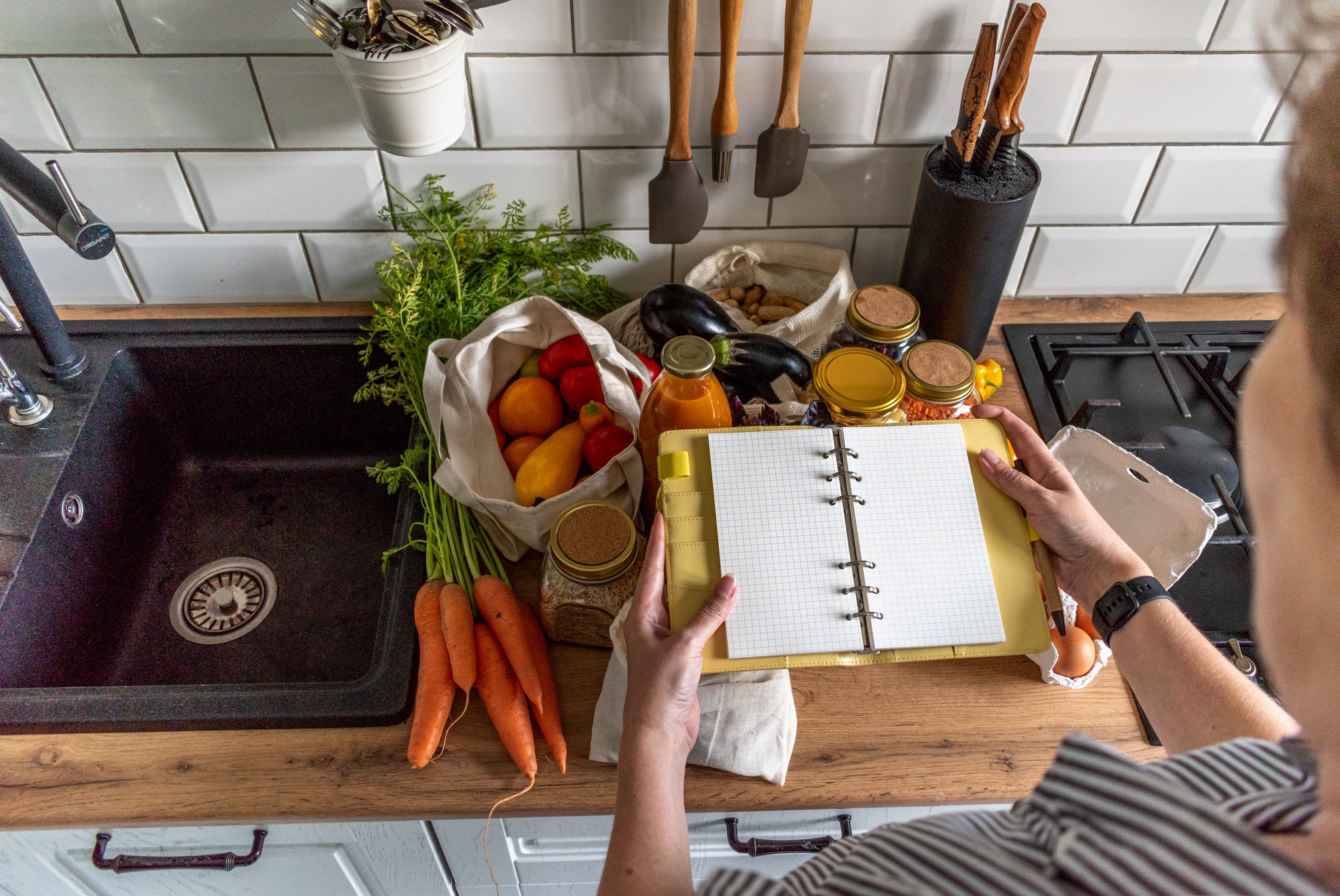 Hands of adult woman writes a shopping list in notebook. Zero waste. Free plastic concept.