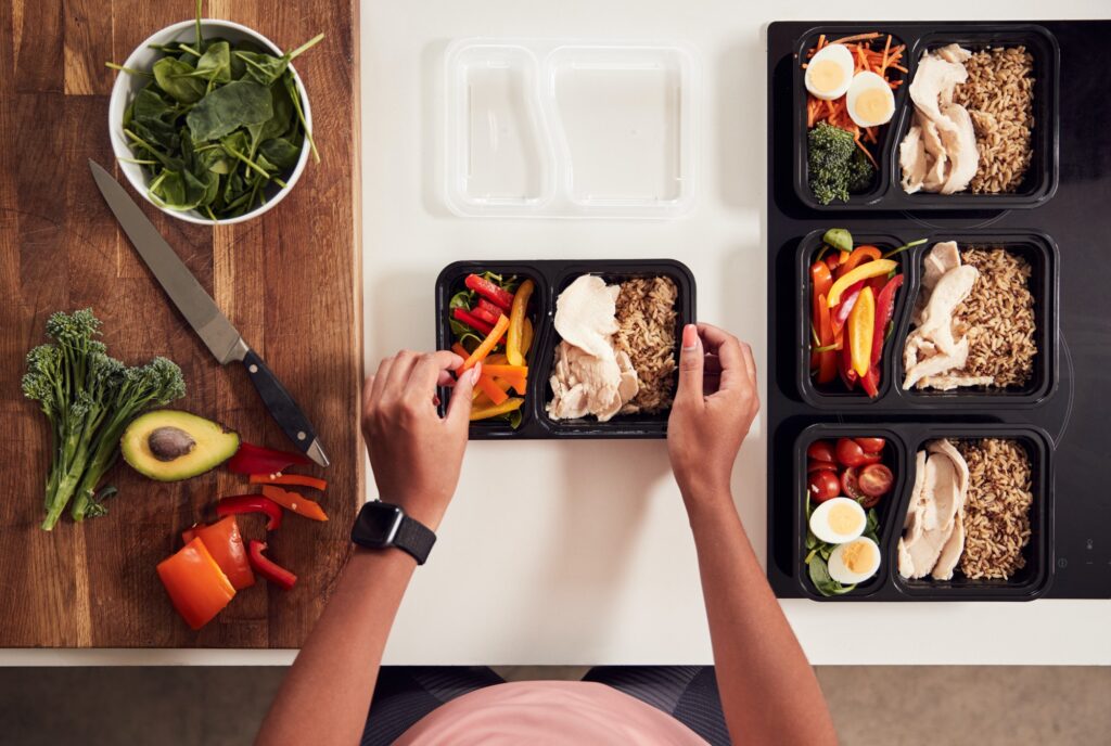 Overhead Shot Of Woman Preparing Batch Of Healthy Meals At Home In Kitchen